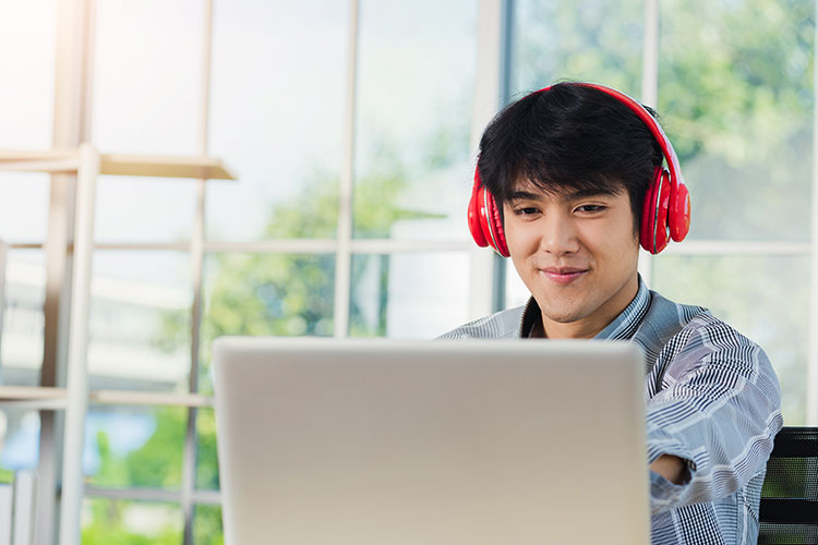 Man with headphones on computer. Man with red headphones on computer.