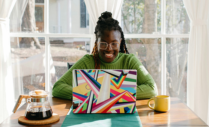 woman on a colorful laptop typing and smilin