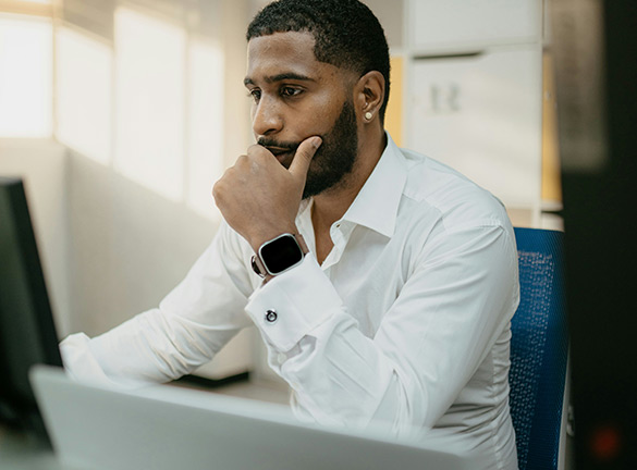 man with hand on his face looking at a computer screen