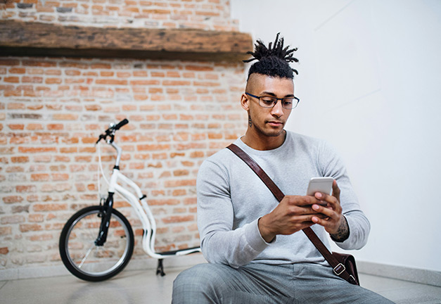 Man with shoulder bag typing on his phone