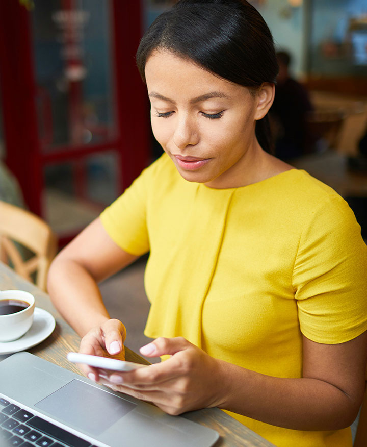 woman in yellow shirt typing on her phone