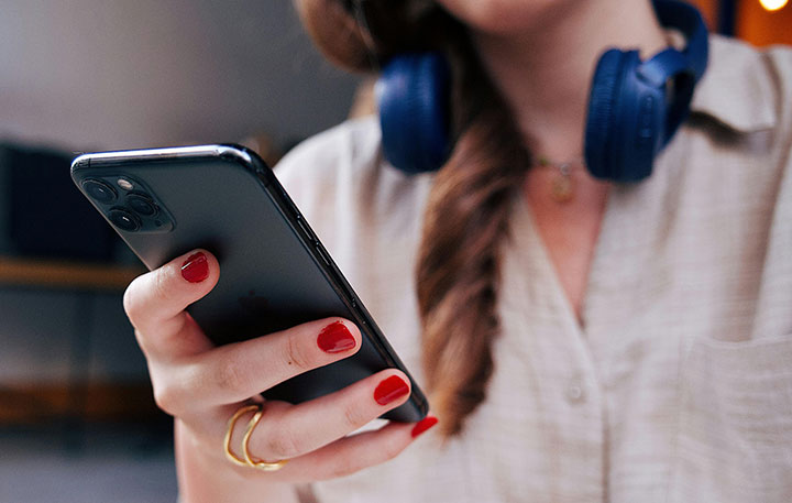 woman wearing blue headphones and holding a black phone