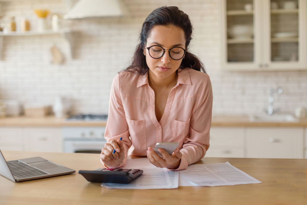 women in pink with cell phone and calculator